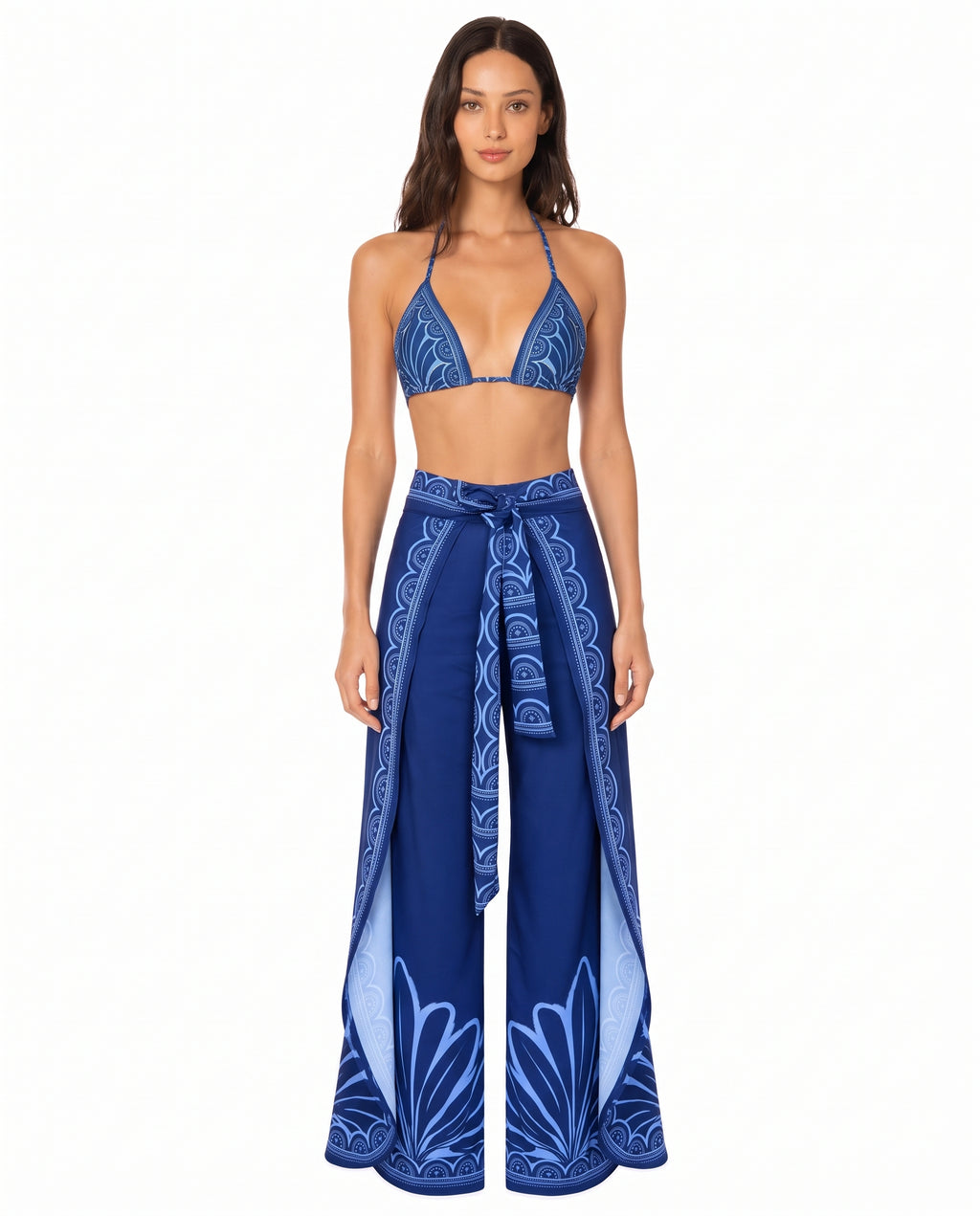 Mujer luciendo un pantalón wrap envolvente de seda azul marino con aberturas laterales y estampado ornamental celeste de la colección Cobalto Egeo.