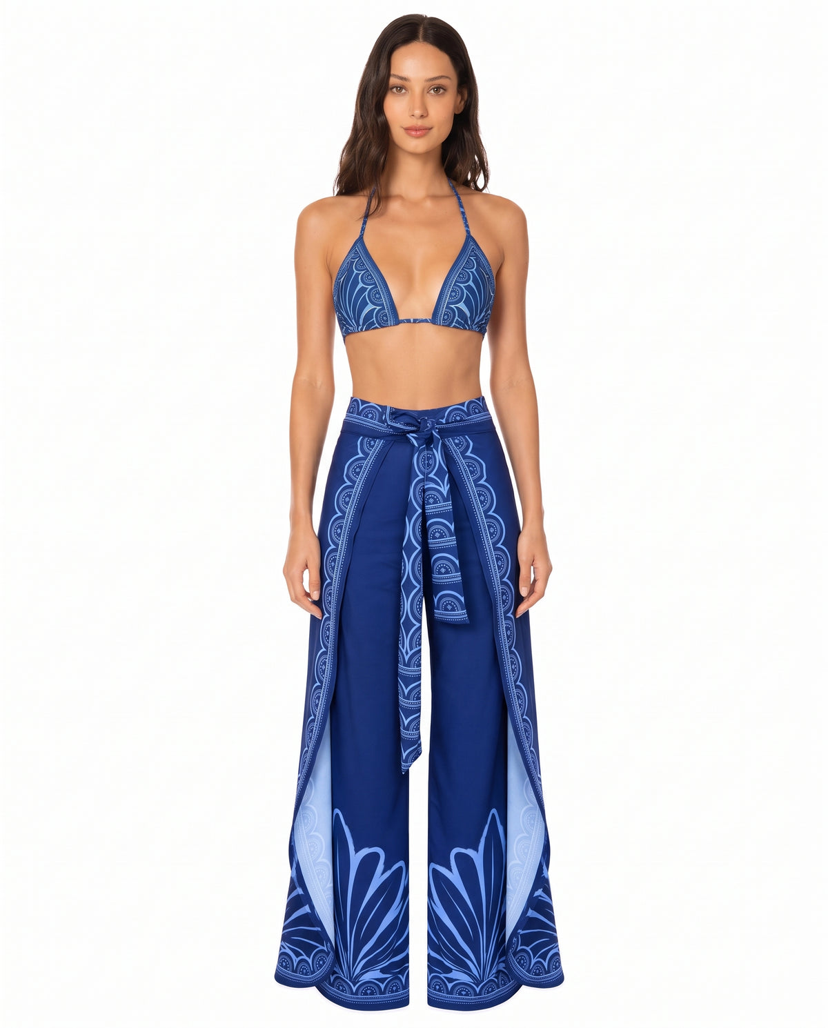 Mujer luciendo un pantalón wrap envolvente de seda azul marino con aberturas laterales y estampado ornamental celeste de la colección Cobalto Egeo.